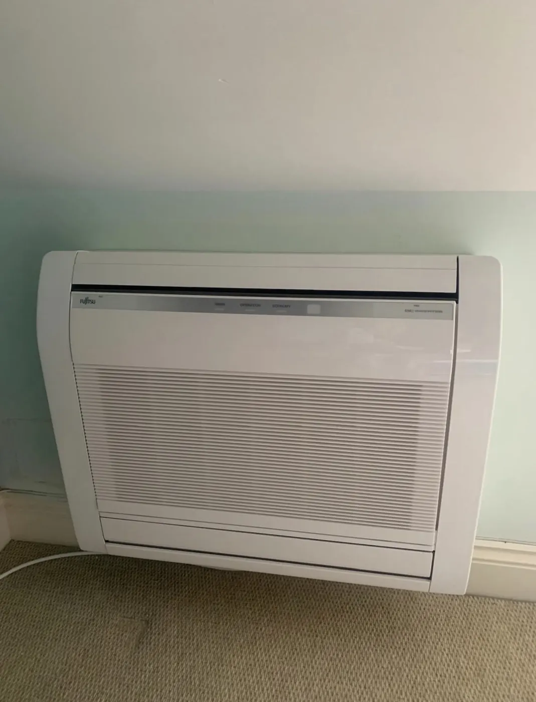 Low-mounted indoor unit against a pale wall